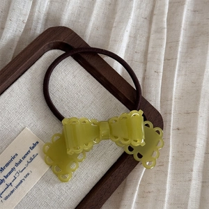 Détail d'une barrette à nœud papillon en acétate vert olive avec des bords ajourés