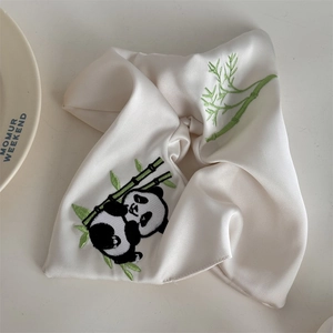 Makroaufnahme von gestickten Panda- und Bambusmotiven auf einem weißen Seidenhaargummi