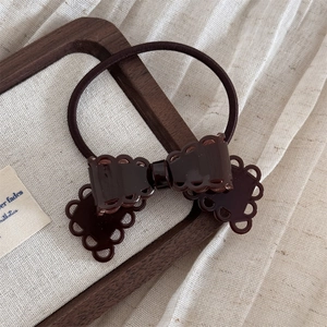 Détail d'une pince à cheveux nœud en acétate marron foncé avec motif dentelle évidé