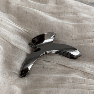 Detailed macro view of the minimalist curved metallic gun-black hair claw with biting teeth