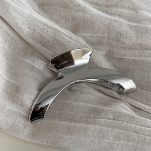 Macro detail of the curved silver metal hair claw clip with a polished mirror finish