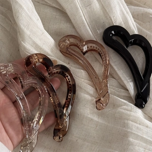 Lot de quatre barrettes bananes en forme de cœur, noir, ambre et transparent sur lin
