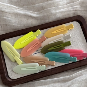 Flat lay of colorful matte jelly hair clips in a wooden tray on linen fabric