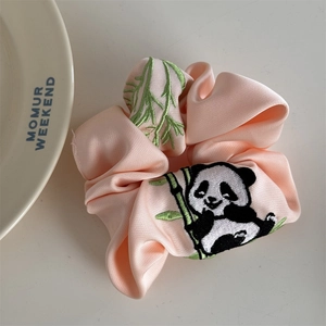 Detailaufnahme des rosa Satin-Haargummis mit süßer Panda- und Bambusstickerei