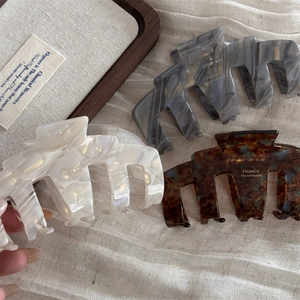 Retro acetate shark hair claws in tortoise shell and cream colors on a wooden tray
