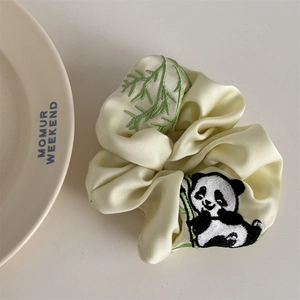 Nahaufnahme des beigen Satin-Haargummis mit Stickerei von Panda und Bambusblättern