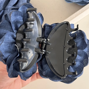 Close-up of a blue denim fabric rose hair claw clip with a strong metal spring mechanism