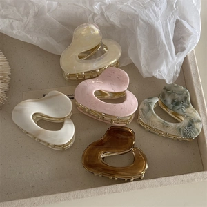 Set of 5 minimalist acetate heart hair claws in cream, pink, and amber on beige tray