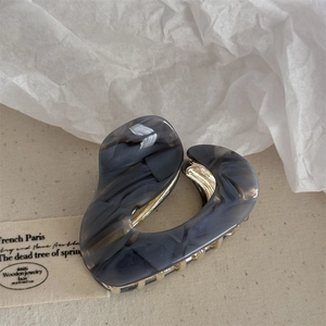 Detail of large marble grey acetate hair claw with elegant golden alloy teeth for women