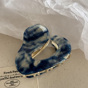 Detail of blue and white marble heart-shaped claw clip with gold metal teeth