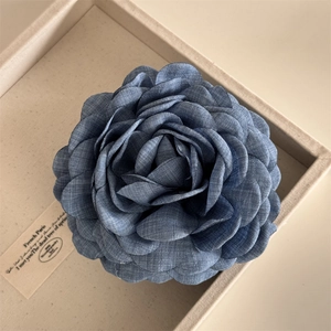 Detailed view of oversized blue denim flower hair claw with layered fabric petals
