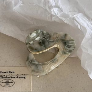 Detail of irregular heart-shaped acetate hair claw with grey and white marble texture