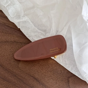 Detailed macro view of the brown acetate clip with gold France Handmade logo