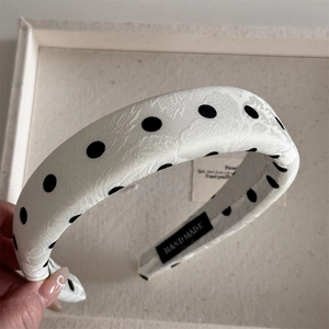 Detail of white jacquard headband with black polka dots and handmade inner label