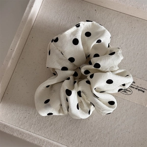 Detail of white scrunchie with black polka dots featuring delicate jacquard fabric texture