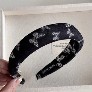 Detail of handmade black headband with white butterfly print and textured fabric