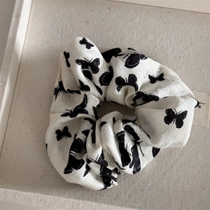 Close-up of white silk scrunchie with black butterfly prints in a fabric tray