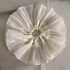 Detail eines übergroßen plissierten cremeweißen Chiffon-Haargummis mit feiner Textur