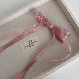 Détail d'une pince à cheveux avec nœud en dentelle rose et longs rubans élégants
