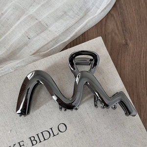 Dettaglio della grande pinza per capelli in metallo grigio scuro con design a onde