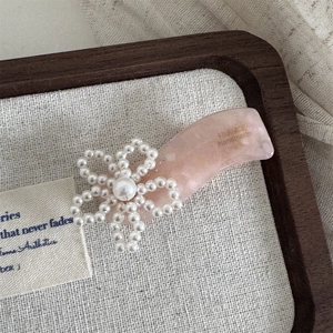 Nahaufnahme der rosa Acetat-Haarklammer mit weißer Perlenblume und Handarbeit-Details