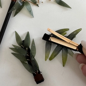 Vue détaillée de la pince à cheveux feuille de bambou verte avec clip en métal doré