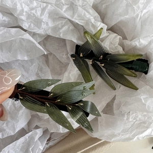 Détail de pinces à cheveux en forme de feuille verte avec gouttes de rosée et fil doré