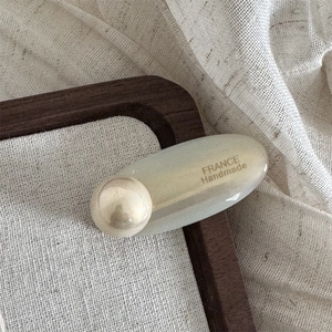 Detailansicht einer ovalen Acetat-Haarspange mit großer Perle und France Handmade Logo