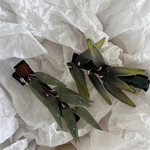 Barrettes à cheveux feuille de bambou en résine verte avec détails de rosée sur fond blanc