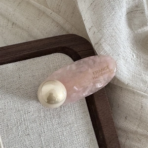 Detailansicht der Haarspange aus rosa Acetat mit Perle und goldener handgemachter Aufschrift
