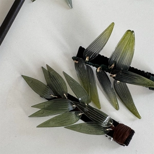 Détail de la pince à cheveux avec feuilles de bambou vertes translucides et fil doré