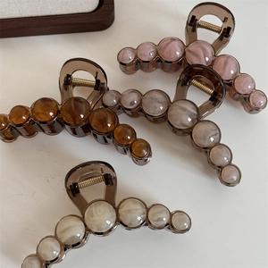 Detail of four colorful marble pattern bead hair claws with golden metal springs