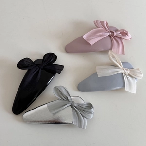 Flat lay showing four colorful bow hair clips with different fabric and metallic finishes