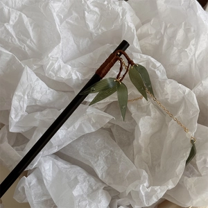Détail d'épingle à cheveux feuille de bambou avec pompon doré et feuille de résine verte