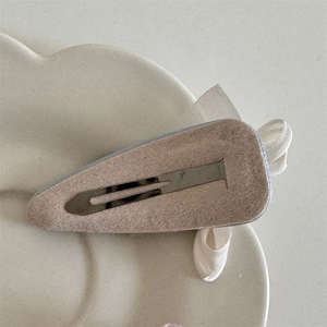 Detail view of handmade bow hair clip with beige felt backing and silver metal BB clip base