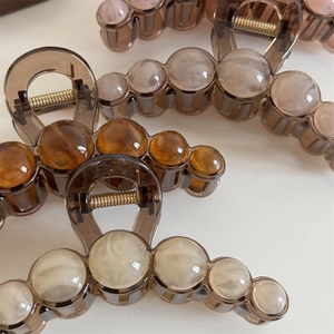 Close-up of large round bead hair claws in amber and cream for thick hair styling