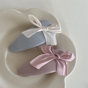 Detailed view of handmade fabric bow hair clips in soft gray and dusty rose tones