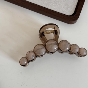 Detailed view of large marble bead hair claw clip in amber and cream resin with metal spring