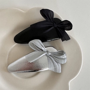 Close-up of elegant bow hair clips in black and silver on a white ceramic plate