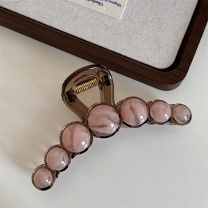 Detail of large amber hair claw clip with eight pink marble texture decorative beads