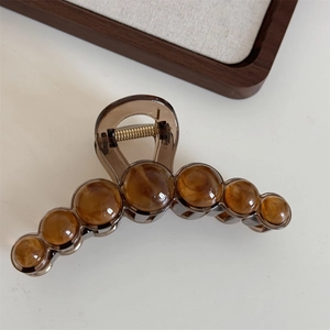 Detailed view of amber resin hair claw clip with round bead accents and gold metal spring