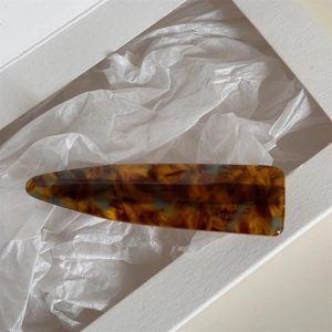 Detailed close-up of handmade amber acetate hair clip with FRANCE Handmade engraving
