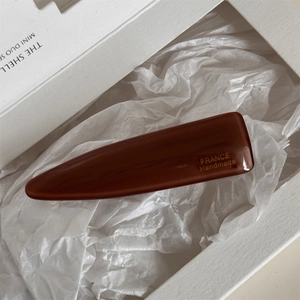 Detailed macro view of brown acetate hair clip with France Handmade gold engraving