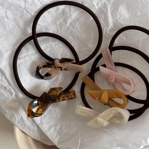 Eleganti elastici per capelli in acetato con nodi in leopardo e ambra su carta bianca