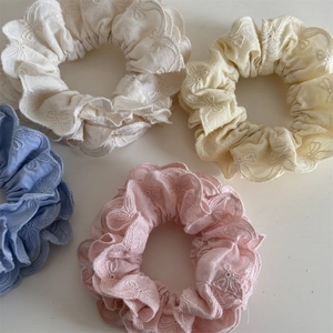 Détail de chouchous aux tons pastels avec broderie florale et bords en dentelle
