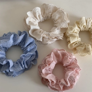 Détail de quatre chouchous pastel avec broderie florale en bleu, blanc, jaune et rose
