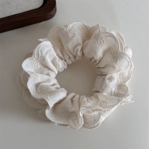 Détail du chouchou couleur crème avec broderie de dentelle délicate en forme de papillon