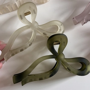 Détail des pinces à cheveux nœud crème et vert olive avec une finition mate élégante