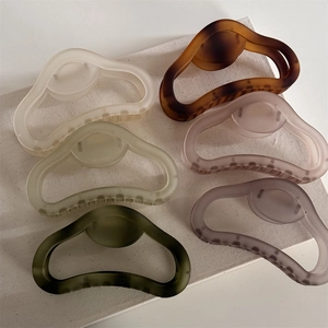 Flat lay of large matte hollow claw clips in six Morandi colors on white canvas