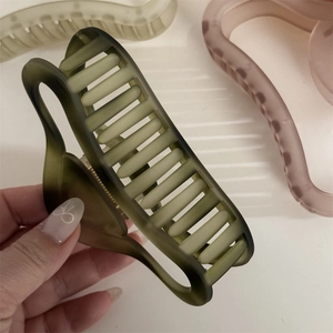 Detailed close-up of a matte olive green large hair claw clip held in hand for scale